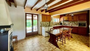 A kitchen with wooden beams, a tiled backsplash, and a central island with chairs.