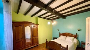 A bedroom with a wooden bed, a wardrobe, and a ceiling with exposed beams.