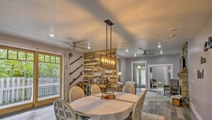 A dining area with a round table, chairs, and a view of the outdoors through large windows. - < 1 Mi to Dtwn Ludington: Bright Lower-level Unit (Ludington)