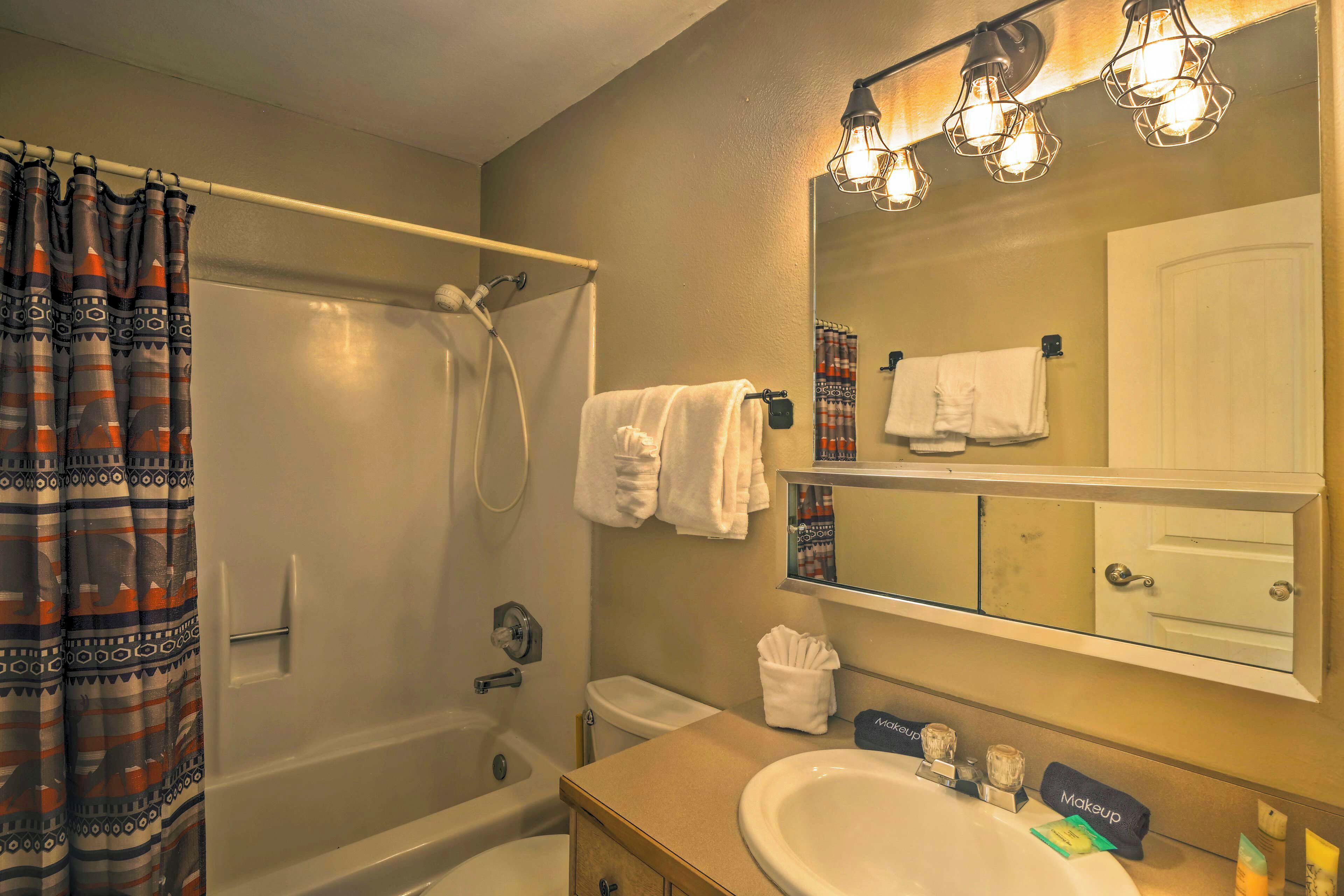 A bathroom with a bathtub, a sink, a mirror, and a shower curtain.