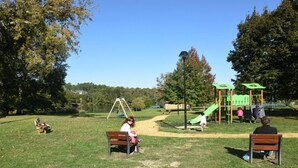 A park with a playground, benches, and a lake in the background. - La Bardane - Brocas - Gîte (BROCAS)