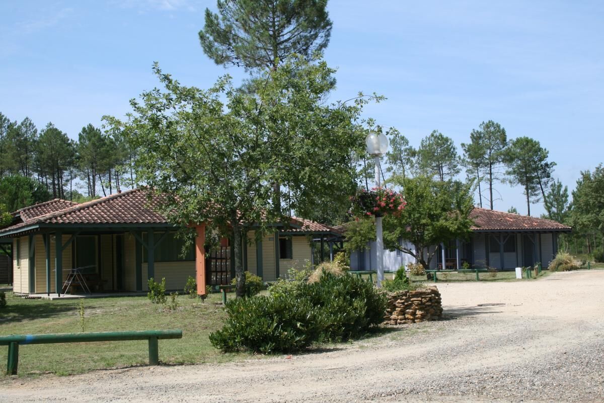 A rustic building with a tiled roof, surrounded by greenery and a gravel path. - La Bardane - Brocas - Gîte (BROCAS)