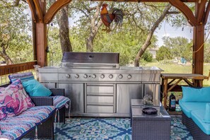 An outdoor kitchen area with a grill, seating, and a decorative rooster.