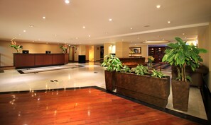 A hotel lobby with a reception desk, seating area, and potted plants. - Hotel Windsor House Inn By GEH Suites (Bogotá)
