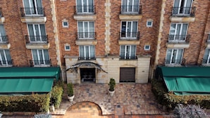 A multi-story brick building with balconies, a central entrance, and a tiled courtyard. - Hotel Windsor House Inn By GEH Suites (Bogotá)
