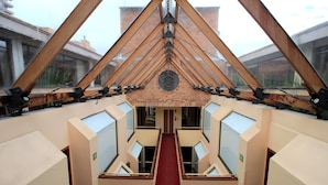 A modern hotel interior with a central red carpet, skylights, and a brick wall with a circular window. - Hotel Windsor House Inn By GEH Suites (Bogotá)