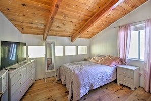Ein Schlafzimmer mit Holzboden, einem Bett mit rosa Bettwäsche, einem Schminktisch, einem Nachttisch und einem Fernseher.