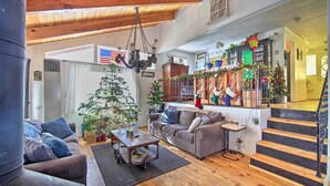 Un salón acogedor con chimenea, una mesa de centro y un sofá. Una escalera conduce a un nivel superior.