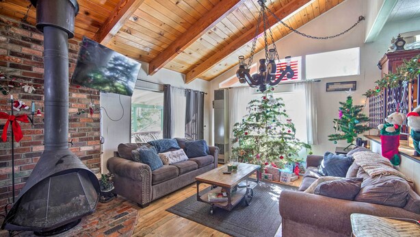 Una sala de estar acogedora con chimenea de ladrillo, vigas de madera en el techo, un ventanal grande y un árbol de Navidad decorado.