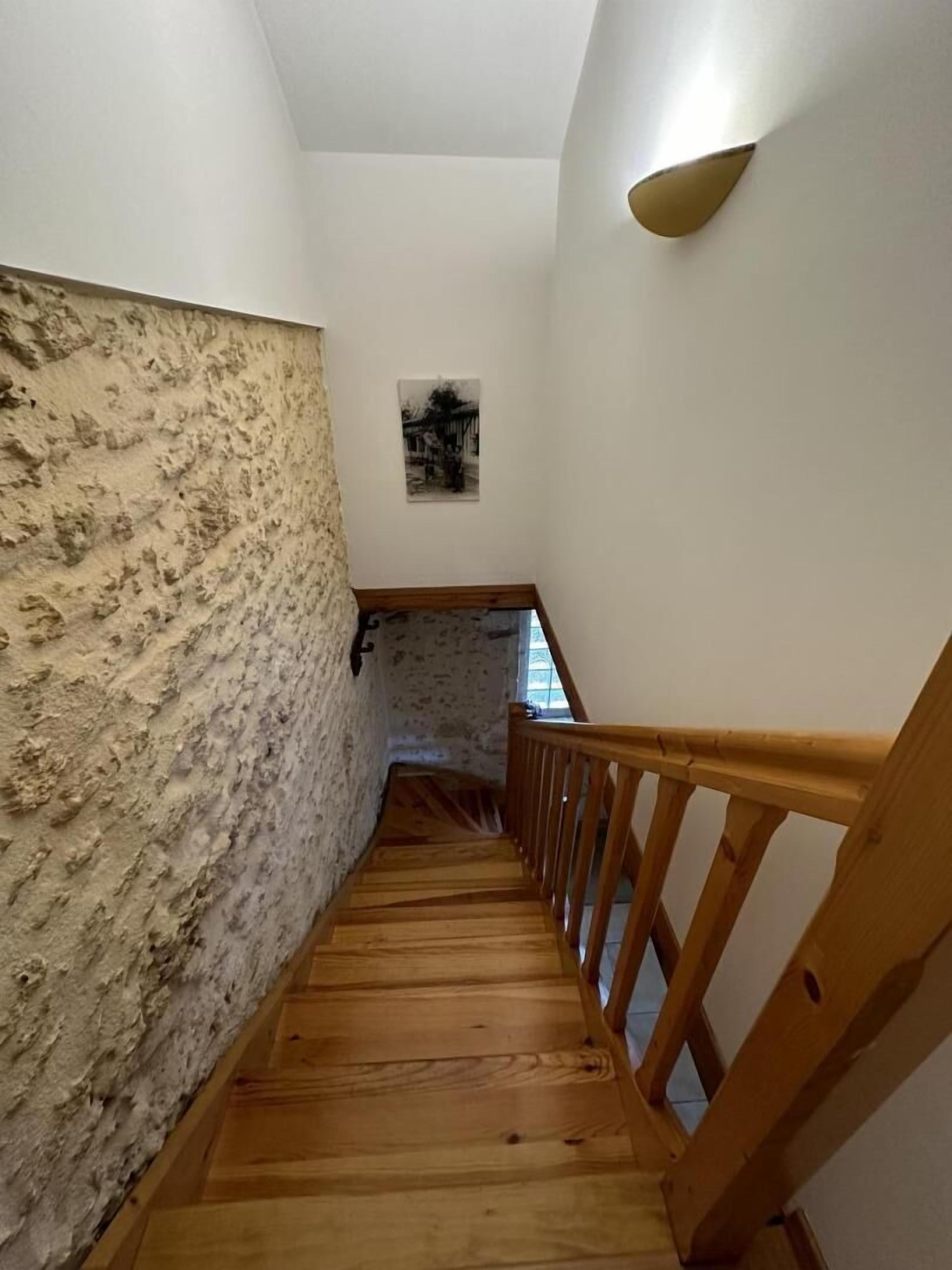 Una escalera de madera con barandilla que conduce a un rellano con un marco de fotos.