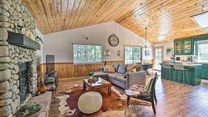 A spacious living room with a stone wall, wooden ceiling, and a large window. - Calming Twin Peaks Family Retreat w/ Views! (Twin Peaks)