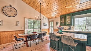 A wooden ceiling, a dining area with a table and chairs, a kitchen with green cabinets, and a large window. - Calming Twin Peaks Family Retreat w/ Views! (Twin Peaks)