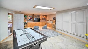 A room with a pool table, a television, and a kitchen area with cabinets and a refrigerator. - Lake Arrowhead Cabin w/ Game Room + Hot Tub! (Lake Arrowhead)
