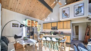 A spacious kitchen with wooden cabinets, a central island with stools, a refrigerator, and a microwave. - Lake Arrowhead Cabin w/ Game Room + Hot Tub! (Lake Arrowhead)