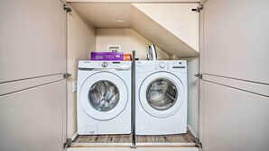 A compact laundry room with two front-loading washing machines and a dryer. - Lake Arrowhead Cabin w/ Game Room + Hot Tub! (Lake Arrowhead)