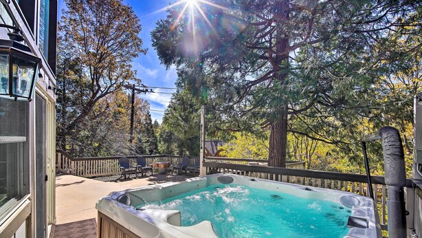A hot tub on a deck with a wooden railing, surrounded by trees and a clear sky. - Lake Arrowhead Cabin w/ Game Room + Hot Tub! (Lake Arrowhead)