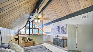 A bedroom with a sloped ceiling, a bed, a desk, and a window. - Lake Arrowhead Cabin w/ Game Room + Hot Tub! (Lake Arrowhead)