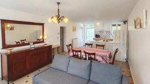Een ruimtelijk ingerichte leefruimte met een bank, eettafel en kitchenette.