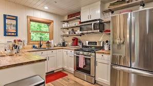 Une cuisine moderne avec des meubles blancs, des appareils en acier inoxydable et des plans de travail en bois.