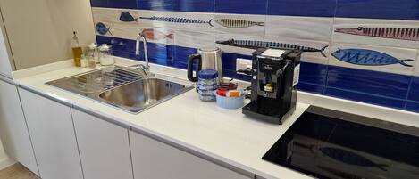 A modern kitchen with a stainless steel sink, a coffee machine, and a microwave.