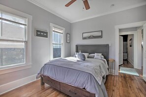Quarto com cama, piso de madeira e ventilador de teto.