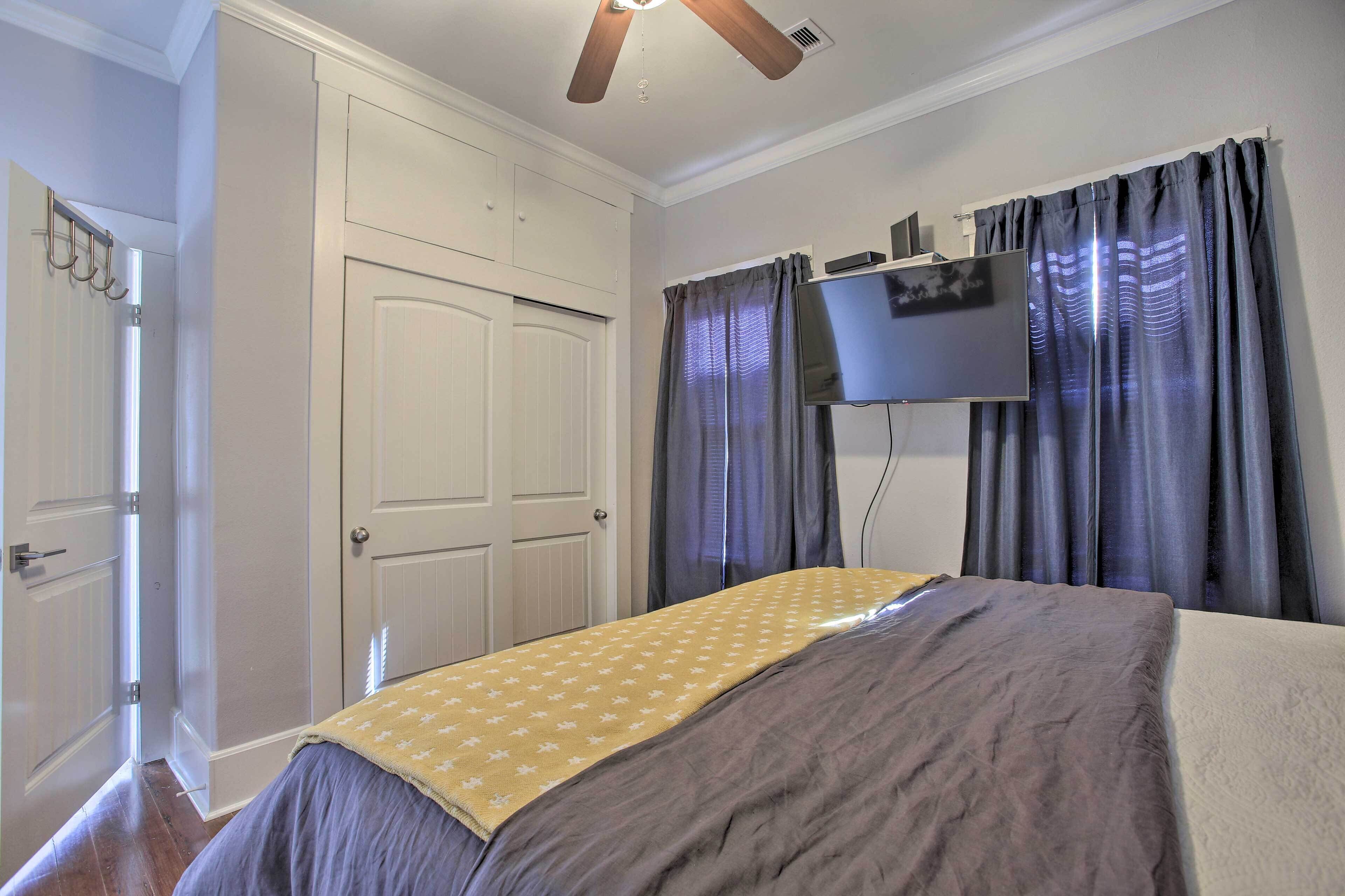 A bedroom with a bed, a ceiling fan, a TV, and a wardrobe.