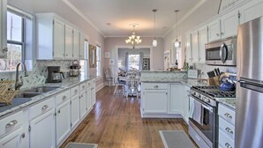 Une cuisine spacieuse avec des meubles blancs, un réfrigérateur en acier inoxydable, une cuisinière et un four à micro-ondes.