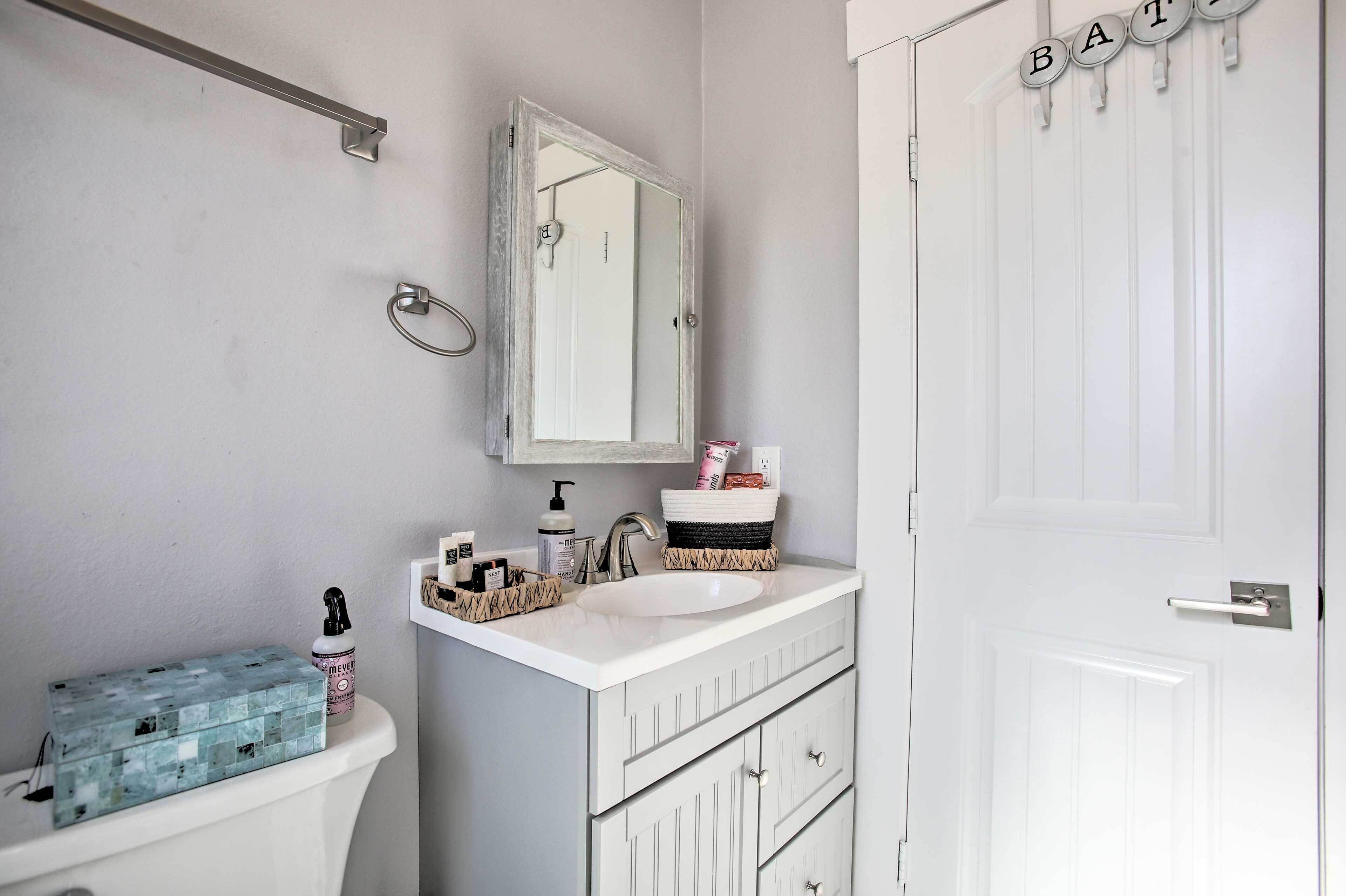 Un bany amb un rentapans blanc, un mirall, un vàter i una porta amb el símbol 'BATH'.
