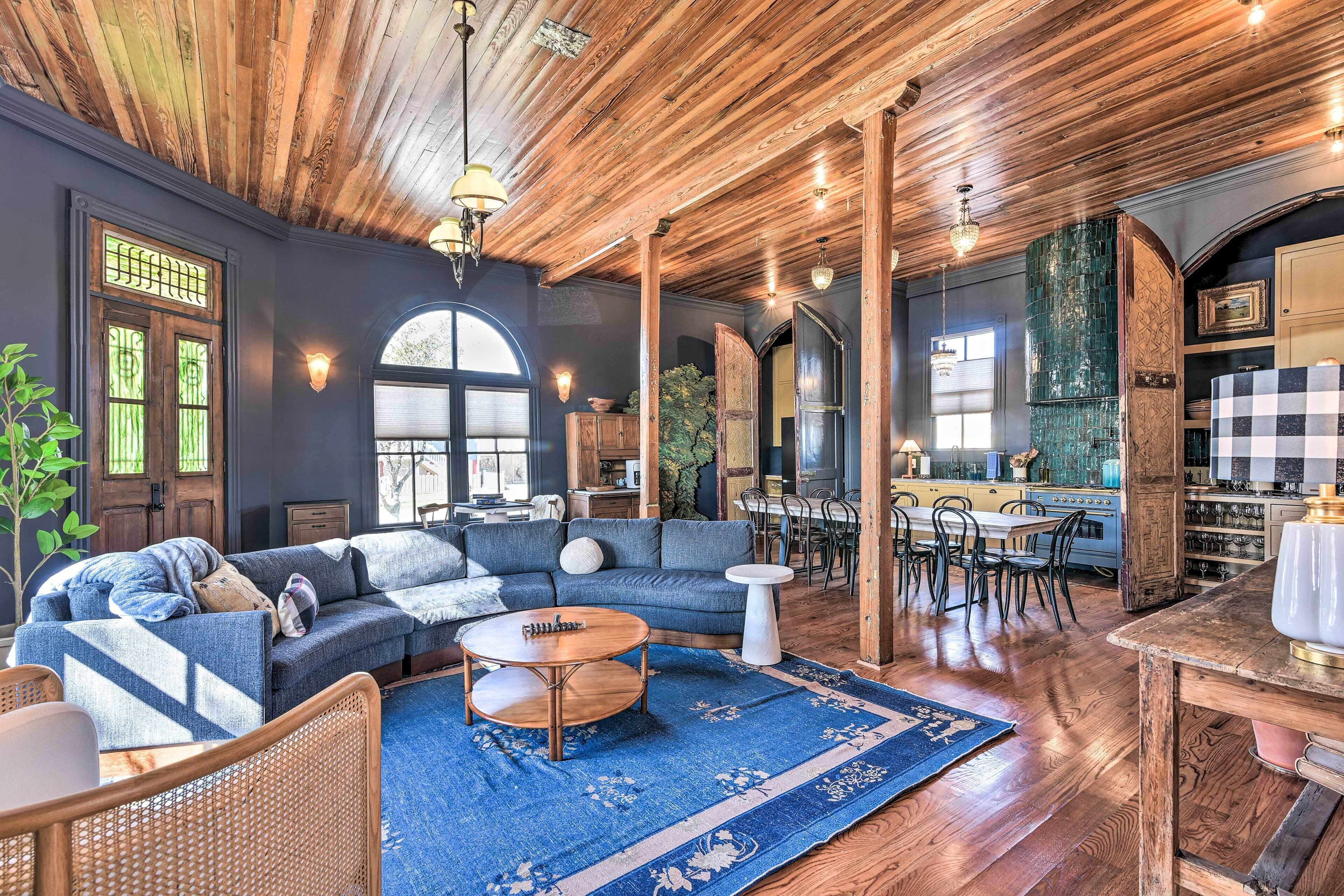 A cozy living room with a blue sofa, wooden coffee table, and a dining area with a checkered tablecloth.
