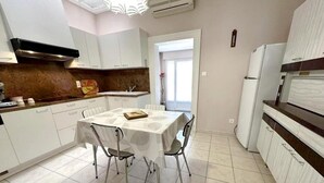 A modern kitchen with white cabinets, a dining table with chairs, and a refrigerator. - Les tilleuls - SOUSTONS (SOUSTONS)