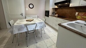 A compact kitchen with a dining table, white cabinets, a built-in oven, and a sink. - Les tilleuls - SOUSTONS (SOUSTONS)