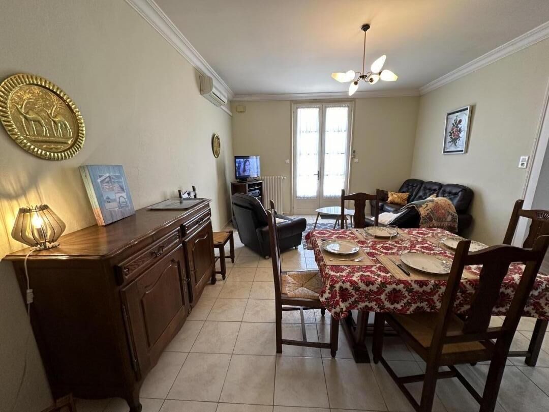 A dining area with a table set for four, a sofa, a television, and a decorative wall piece.