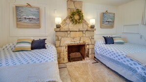 Habitación con dos camas, chimenea de piedra y dos lámparas fijadas a la pared.