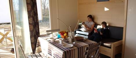 Un comedor con una mesa dispuesta para dos personas, un sofá y vistas al exterior.