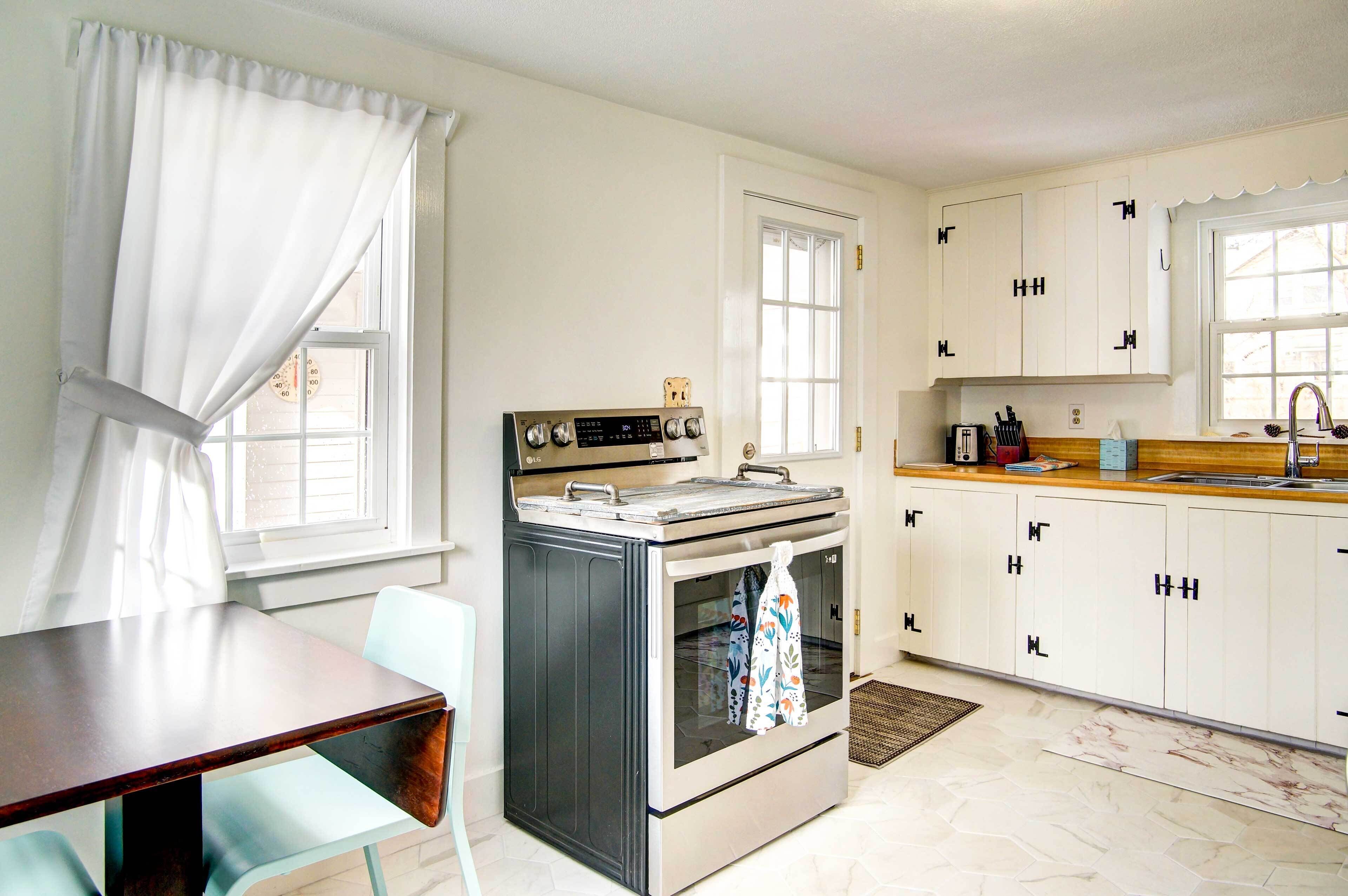 A compact kitchen with a stove, oven, and white cabinets.