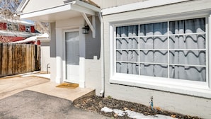 Une maison blanche avec une grande fenêtre, une véranda et une clôture en bois.