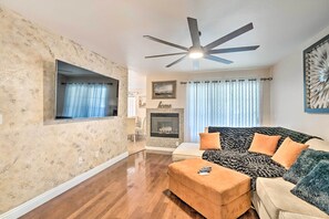 A living room with a fireplace, a ceiling fan, and a large window with curtains. - Walkable Location! Las Vegas Apt: 11 Mi to Strip (Las Vegas)
