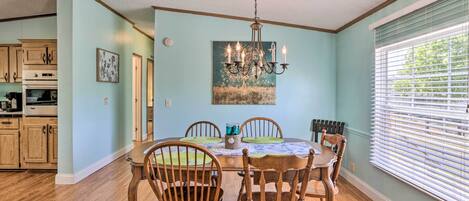 A dining room with a wooden table, chairs, and a chandelier.