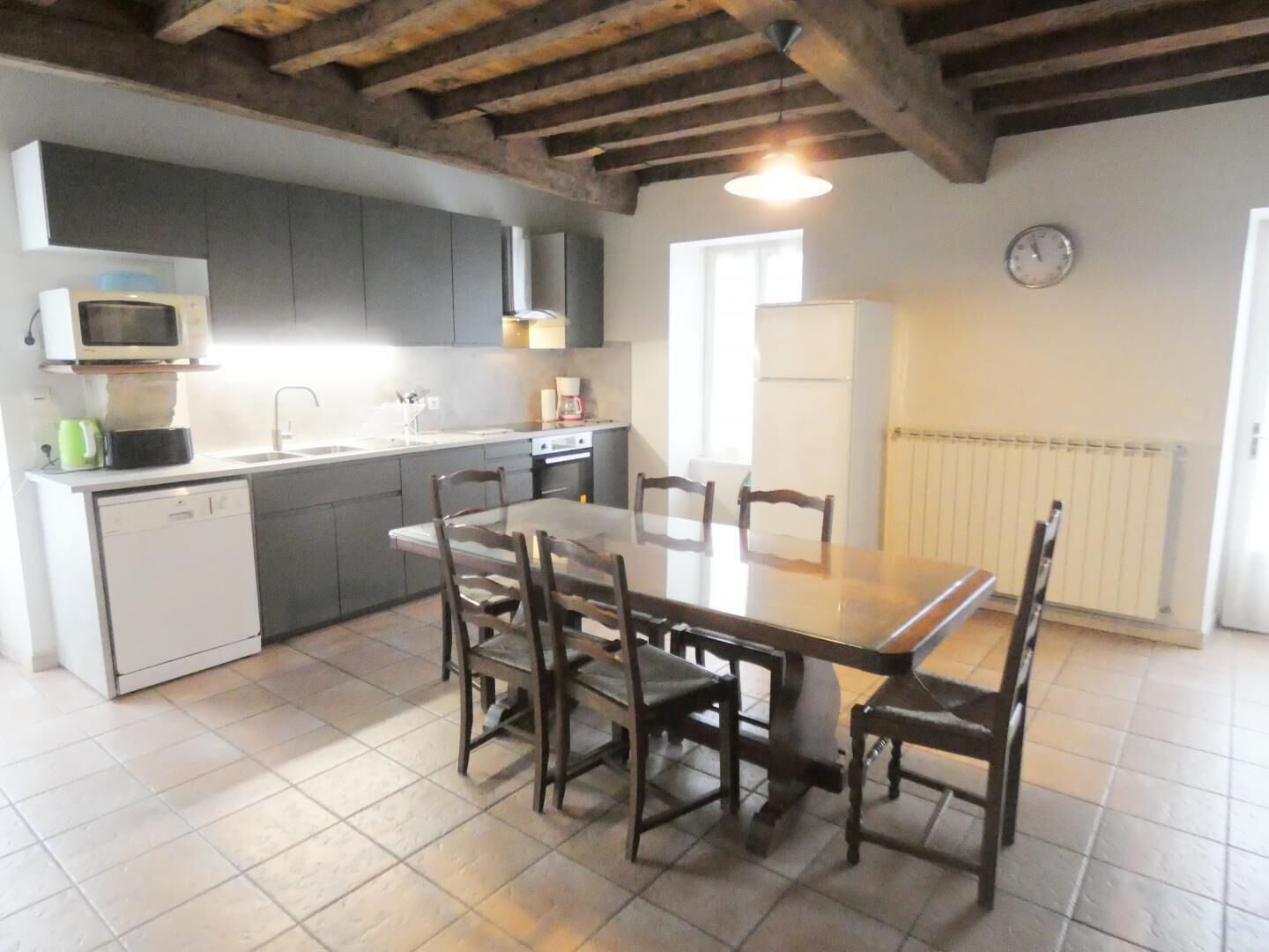 A kitchen with a dining table and chairs, a microwave, a sink, and a stove.