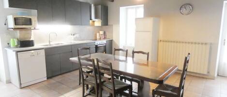 A kitchen with a dining table and chairs, a microwave, a sink, and a stove.
