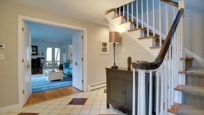 A staircase with wooden steps and white railings, leading to a landing with a lamp and a cabinet.