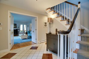 A spacious living area with a staircase, a coffee table, and a lamp. - Falmouth Retreat w/ Deck & Grill, Walk to Beaches! (Falmouth)