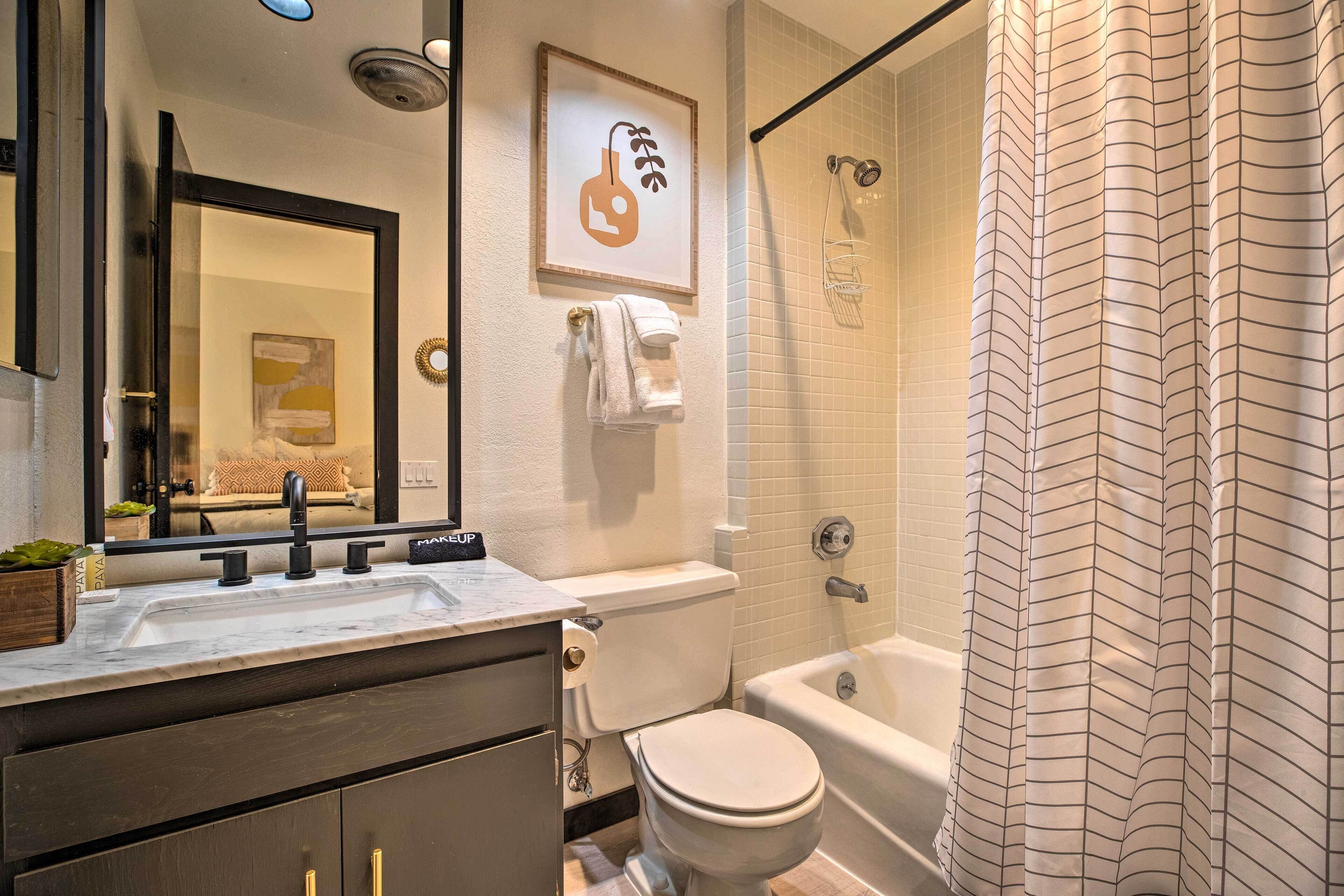 A bathroom with a sink, mirror, toilet, and shower.