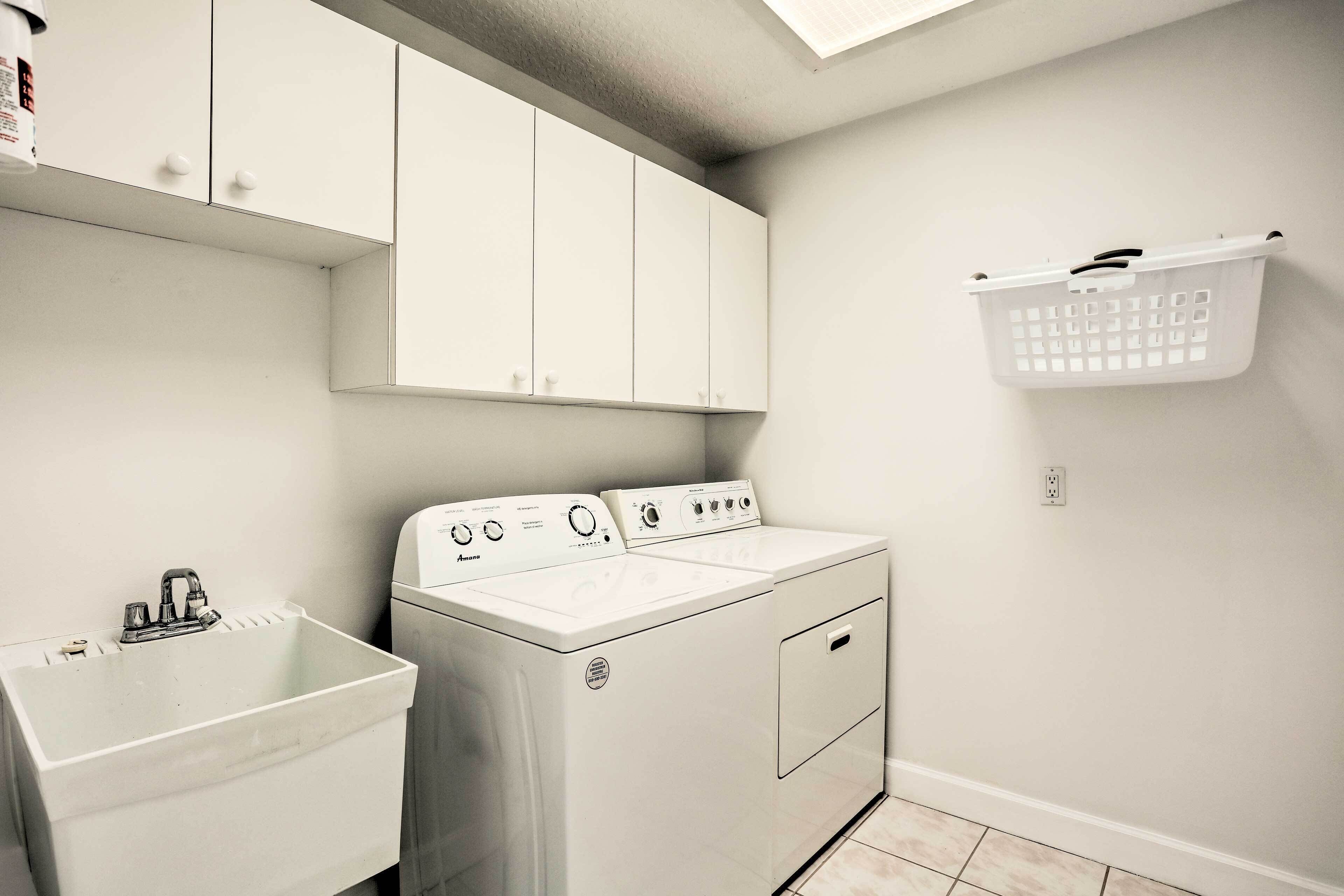 A laundry room with a washing machine, a sink, and a laundry basket.