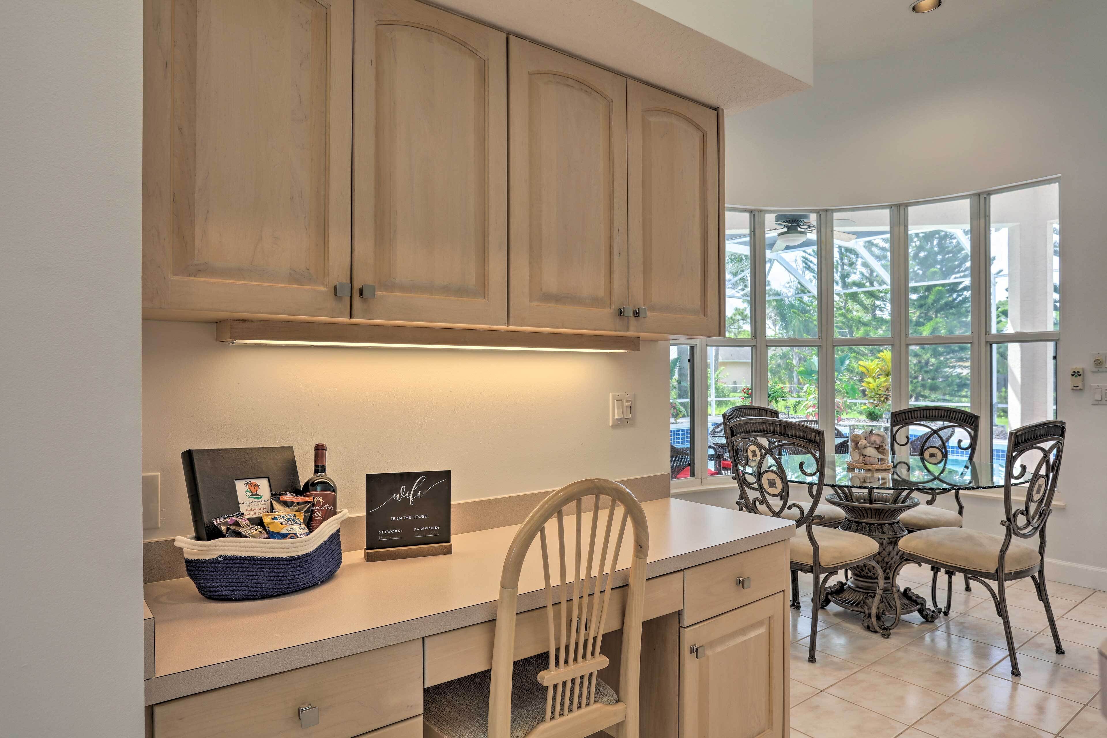 A kitchen with wooden cabinets, a dining table with chairs, and a view of greenery outside.