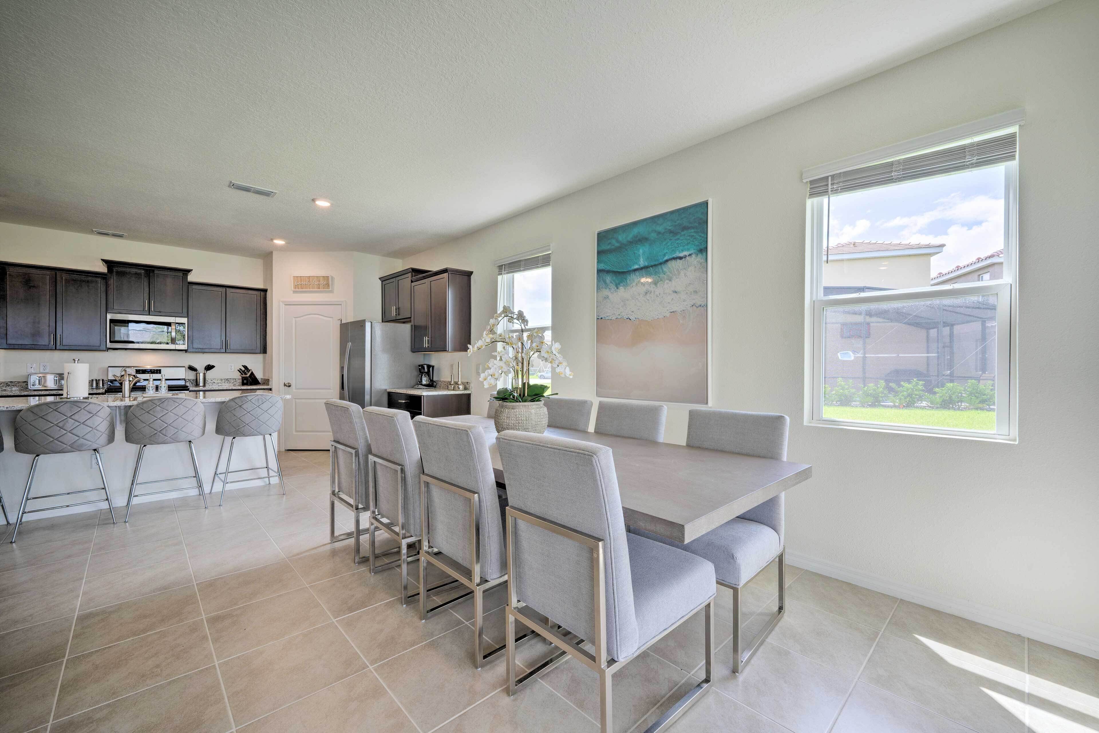 A modern kitchen with dark cabinets, a stainless steel refrigerator, and a large island with bar stools.