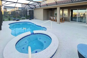 A swimming pool with a hot tub, outdoor seating, and a covered patio area.