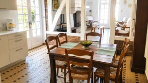 A dining area with a wooden table and chairs, a coffee maker on the counter, and a brick wall.