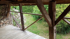 A wooden deck with a stone wall and a view of a garden.