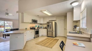 Una cocina moderna con gabinetes blancos, electrodomésticos de acero inoxidable y una isla central.